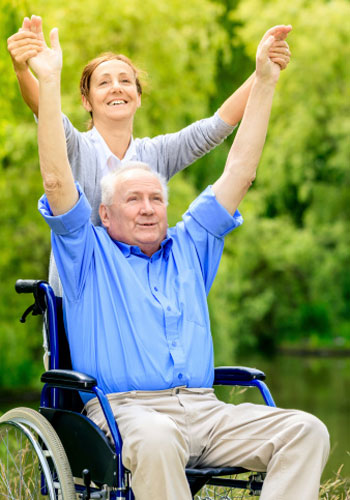Man in wheelchair enjoying outdoor stretches with nurse