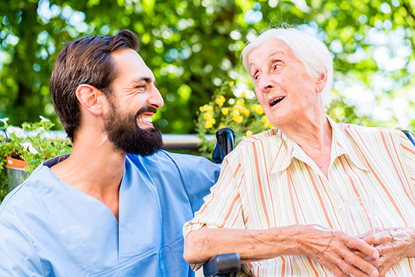 Male nurse and elderly woman talking and laughing