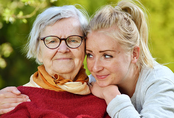 Young woman carefully takes care of an older woman.