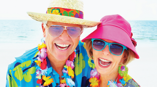 older adult couple dressed in vibrant summer clothing and hats at the beach