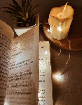 book of poetry lit with string lights sitting next to lit candle