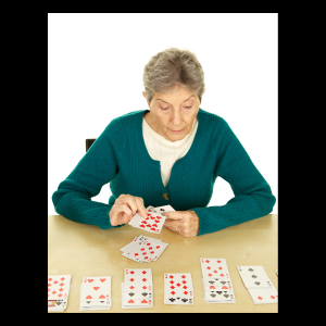 senior woman, in teal green sweater, playing solitaire card game