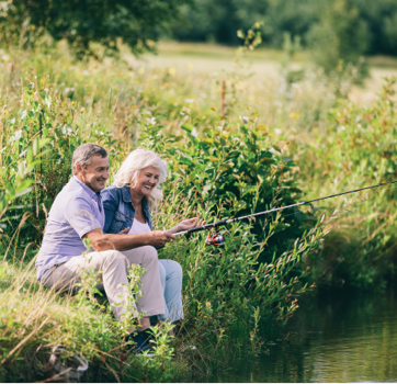 senior couple fishing on river bank