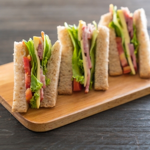 Club sandwich cut into three with ham, cheese, lettuce, and tomato.